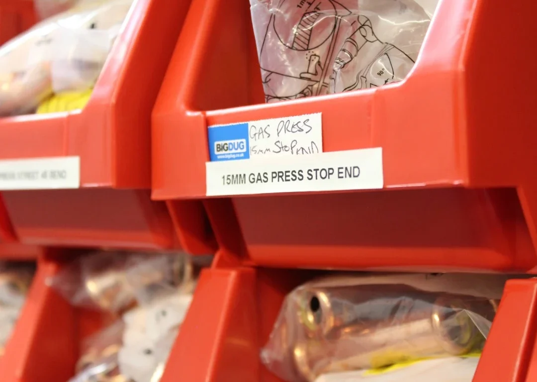 A row of red containers filled with underfloor heating parts and accessories.