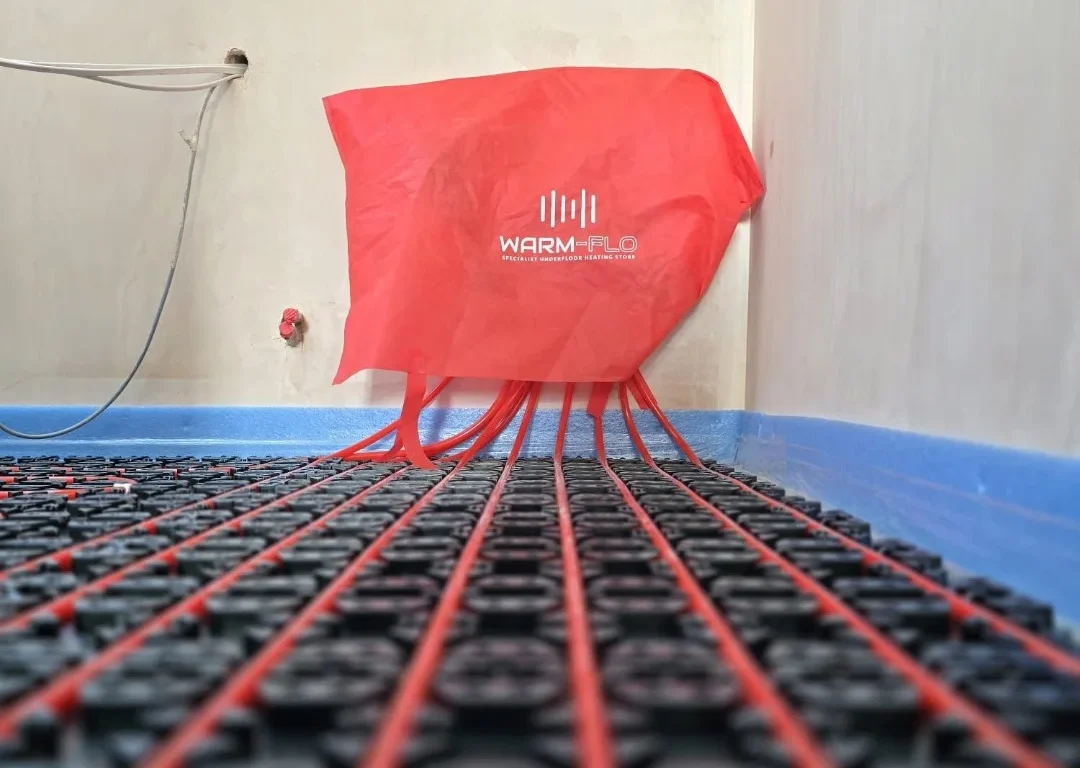 An underfloor heating system installation with a red Warm-Flo cover.