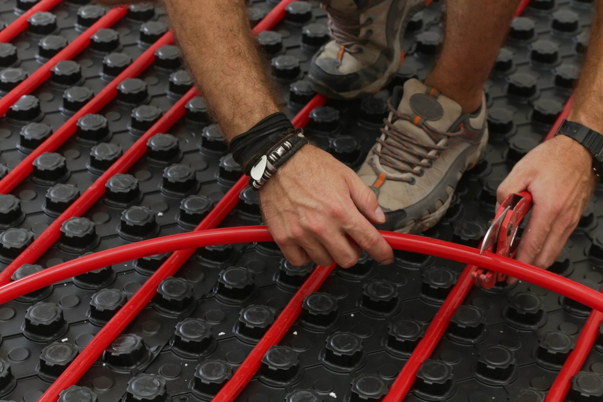 A contractor cutting pipes for an electric underfloor heating system.