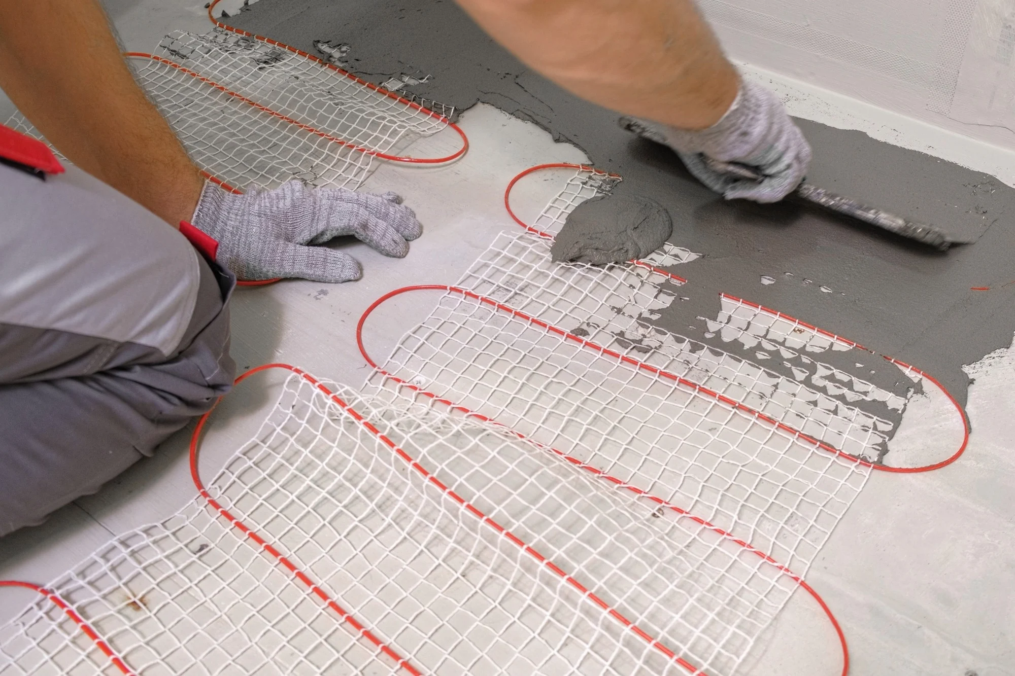 A contractor spreading screed over a water underfloor heating system.